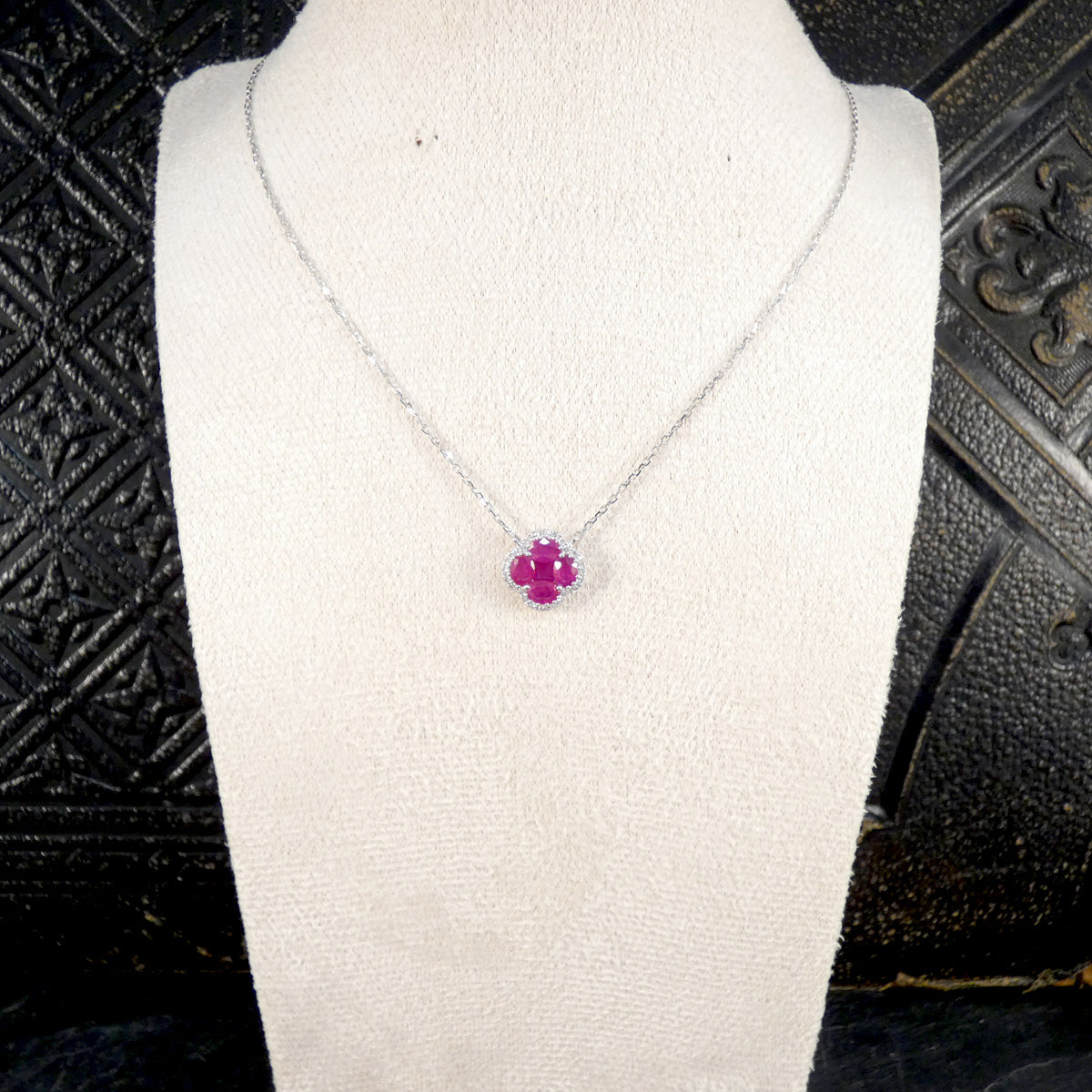 A ruby and diamond necklace shown on a bust.