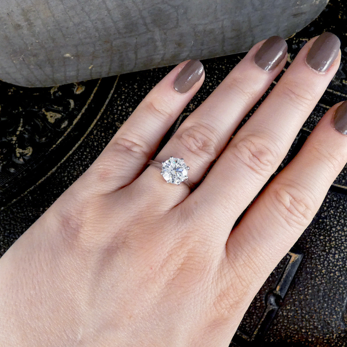 Hand wearing a diamond ring on a textured surface