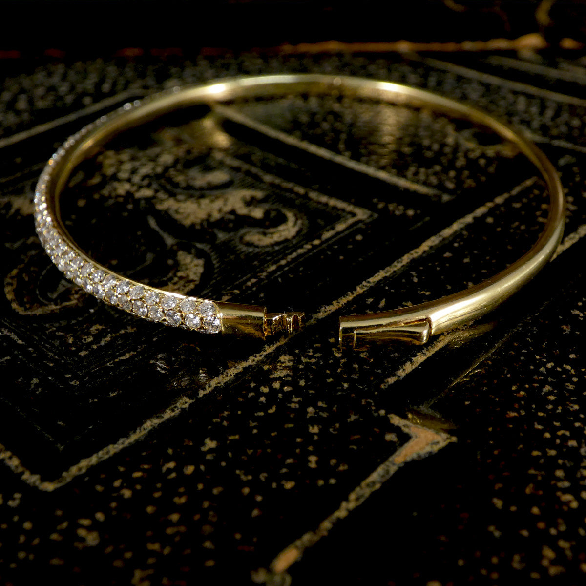 Gold bracelet with diamond accents on a dark textured surface