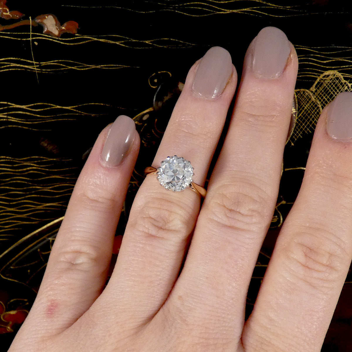 An Old Cushion shaped Mine cut diamond solitaire ring displayed on the hand.
