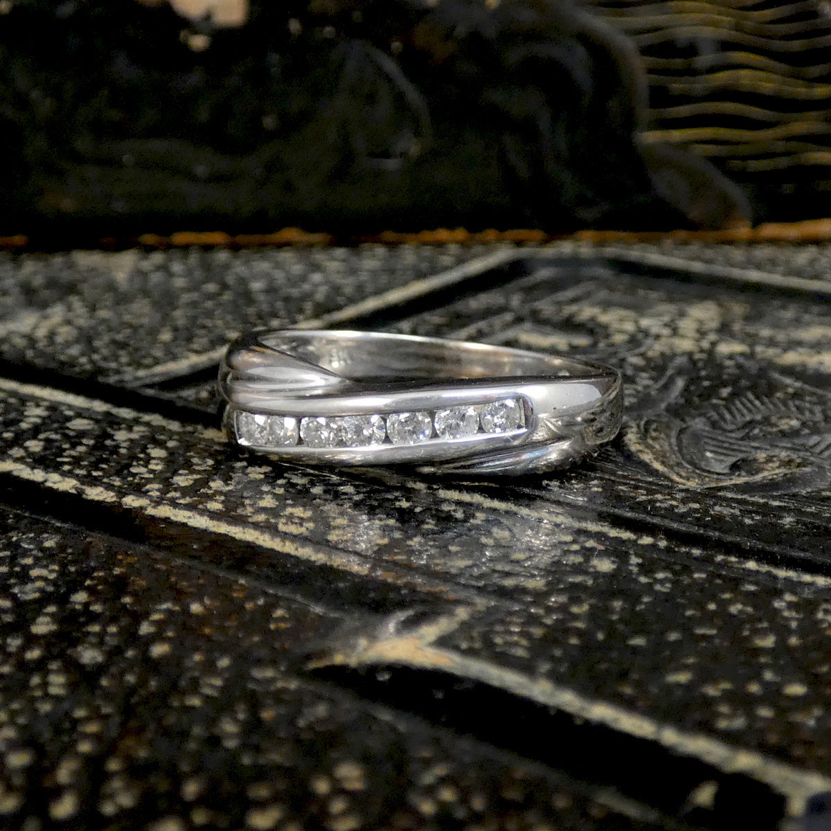 white gold ring with small diamonds on a textured wooden surface