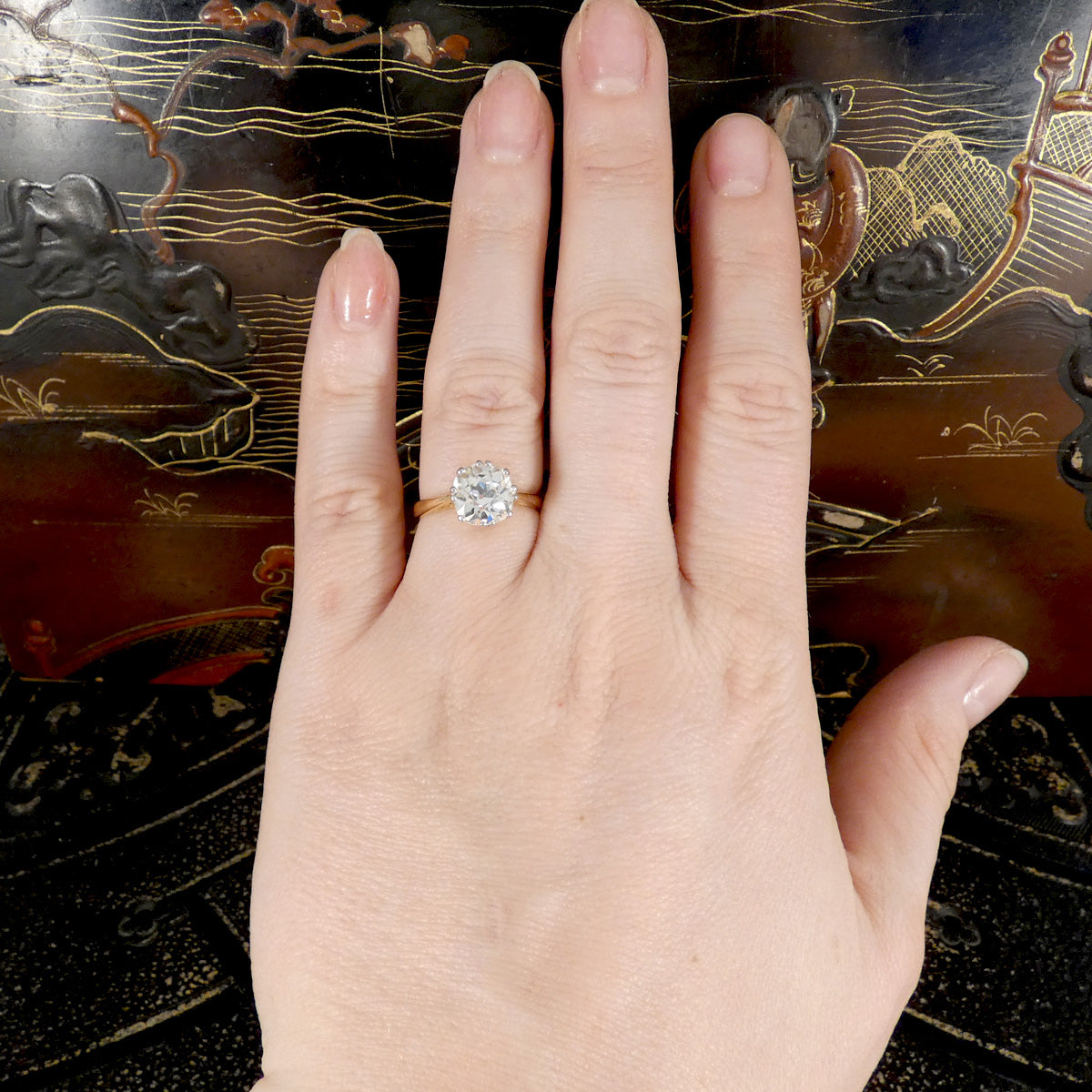 Hand wearing a diamond engagement ring on a decorative background