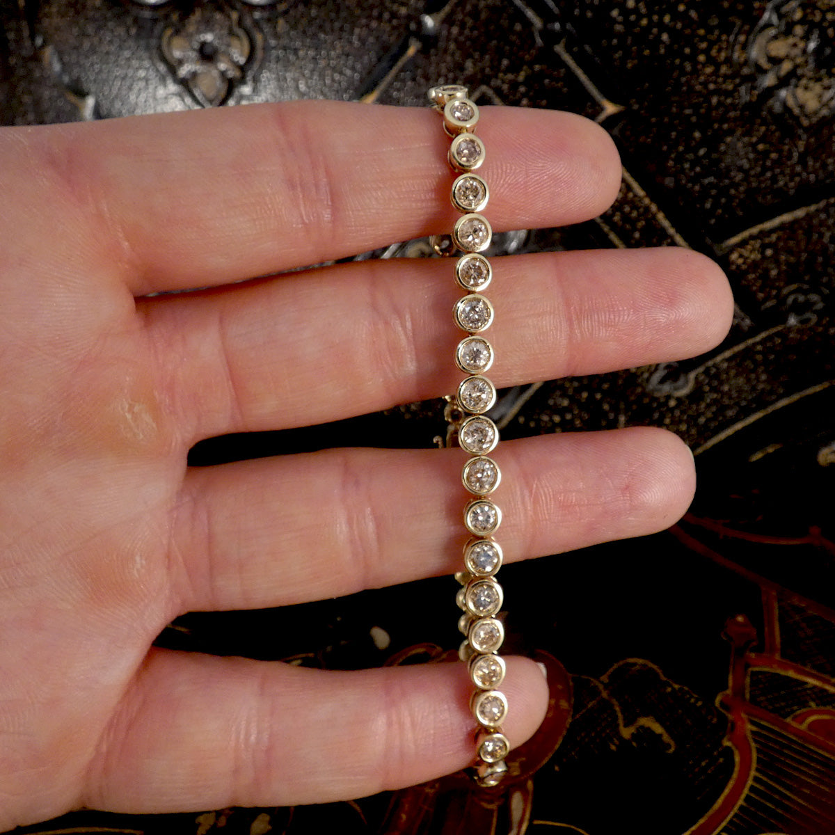 a diamond bezel set tennis bracelet in 9ct yellow gold.
