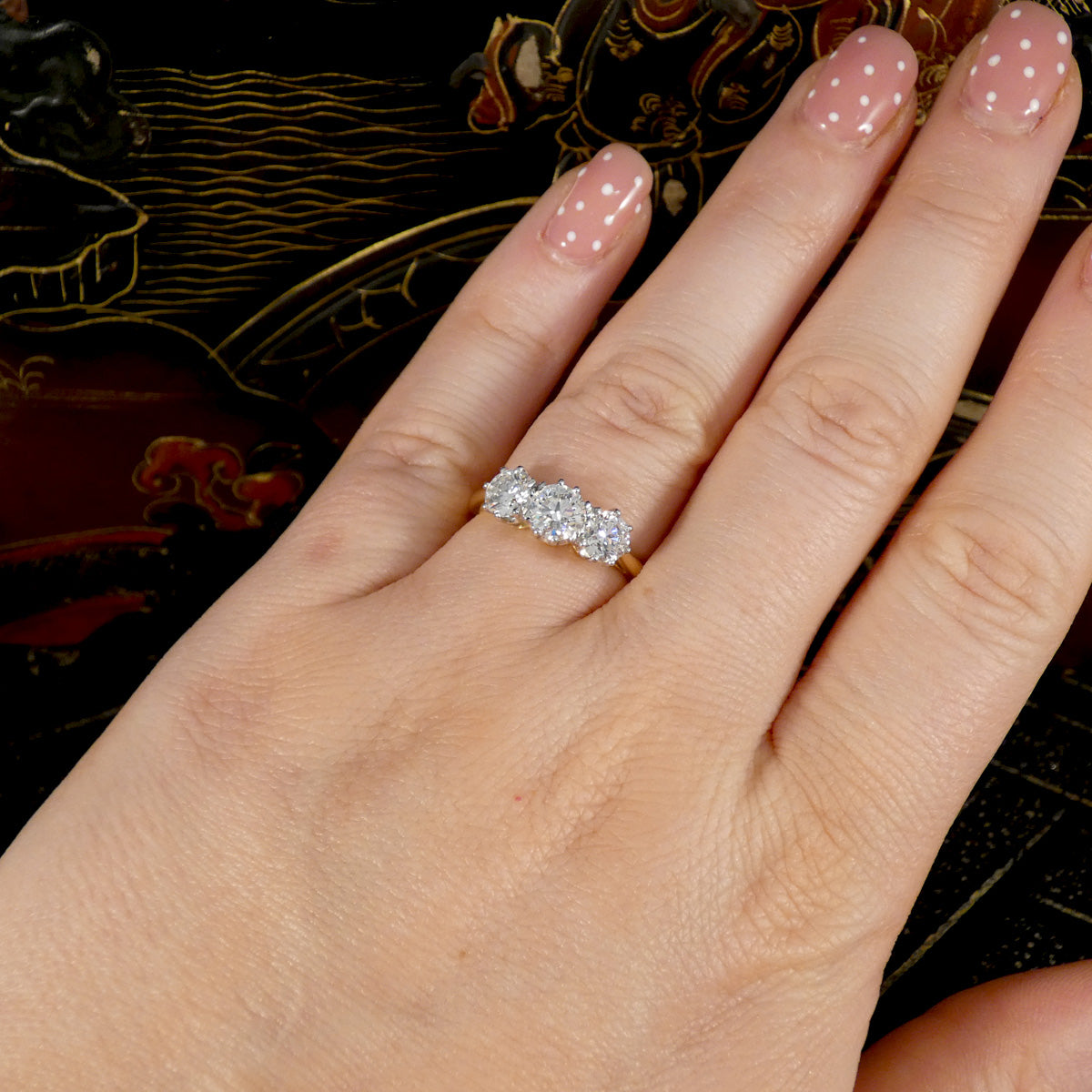 Hand wearing a diamond ring with a decorative background