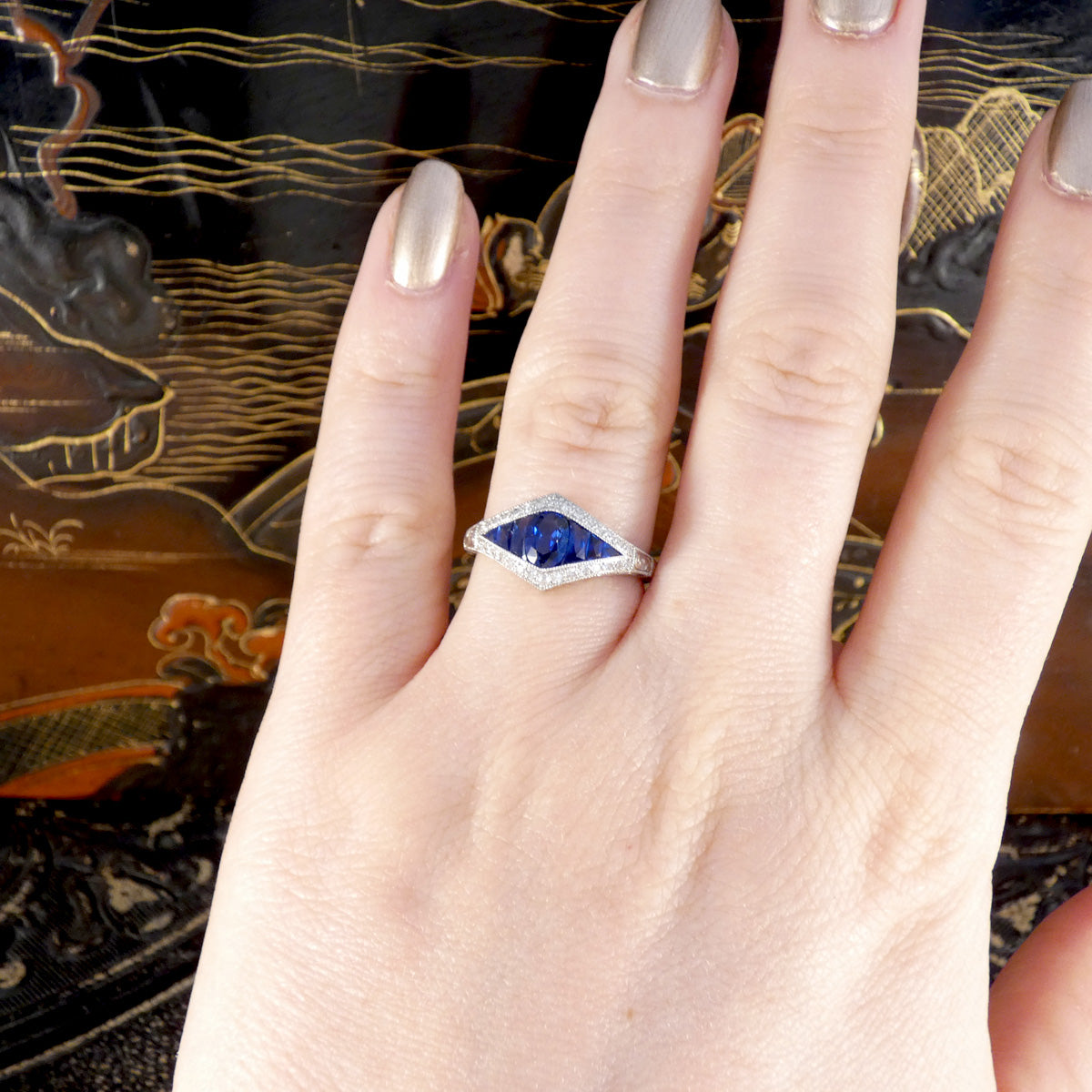 A gorgeous Art Deco style Sapphire and Diamond cluster ring in Platinum. Shown worn on the hand to be seen on ring finger.