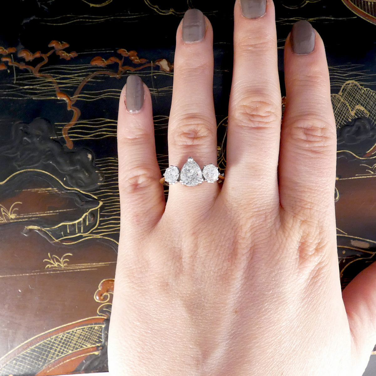 Hand wearing a diamond ring with a decorative background