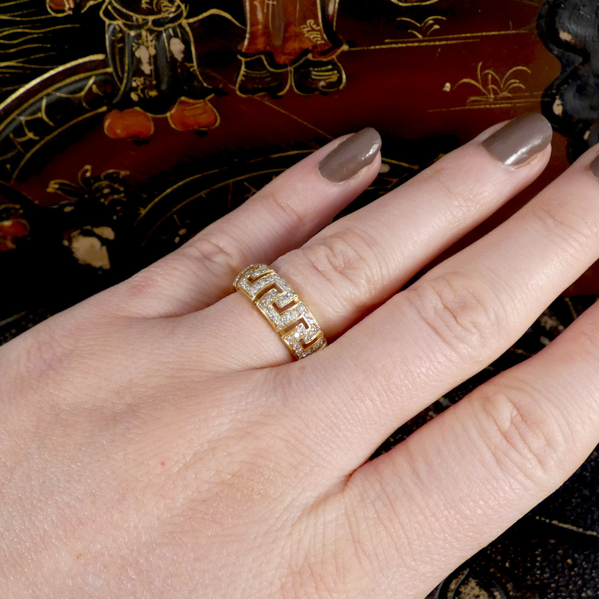 Gold ring on a finger with a decorative background
