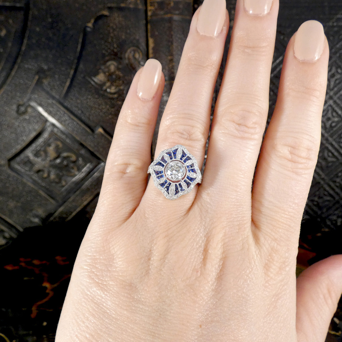 Art Deco Inspired Diamond and Sapphire Cluster Ring in Platinum displayed on the ring finger to see size and shape.