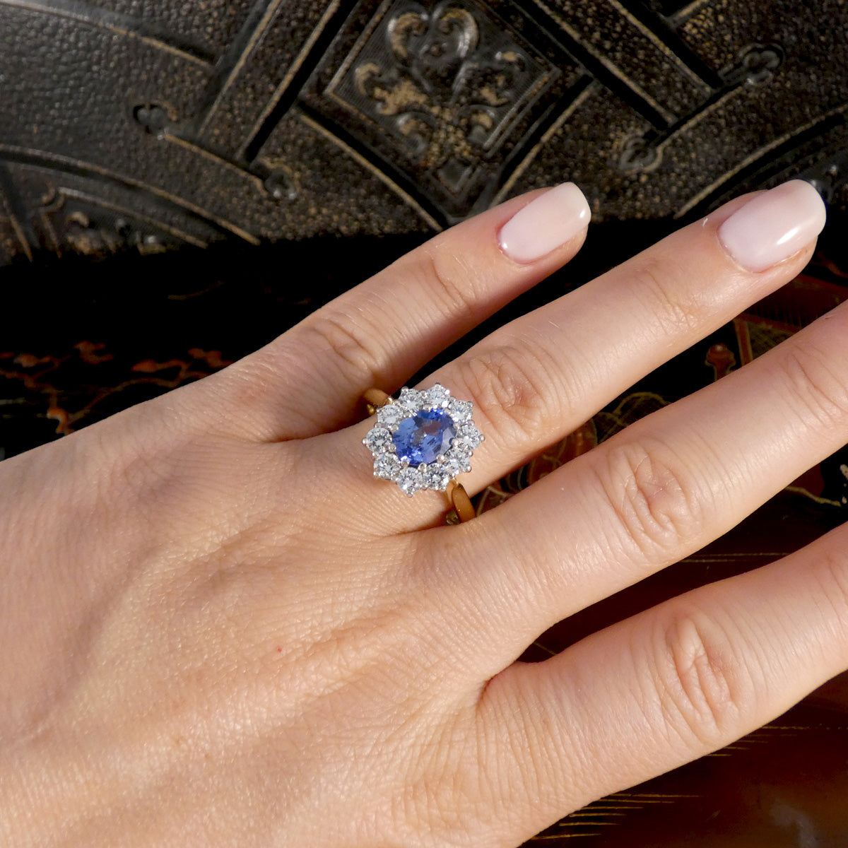 Hand wearing a ring with a blue gemstone on a textured surface