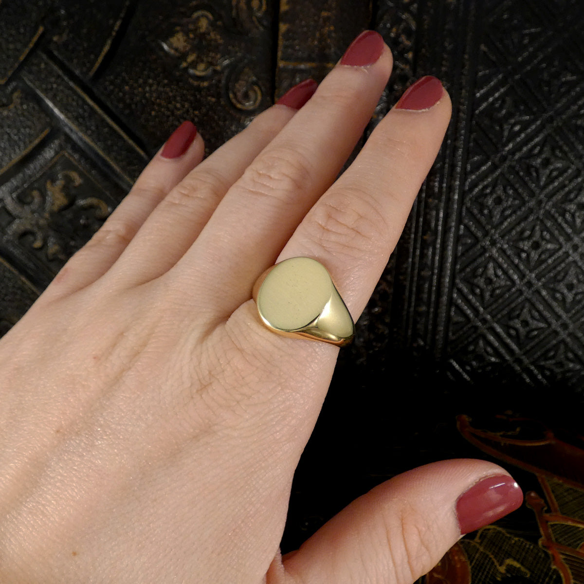 Hand wearing a gold ring with a dark textured background
