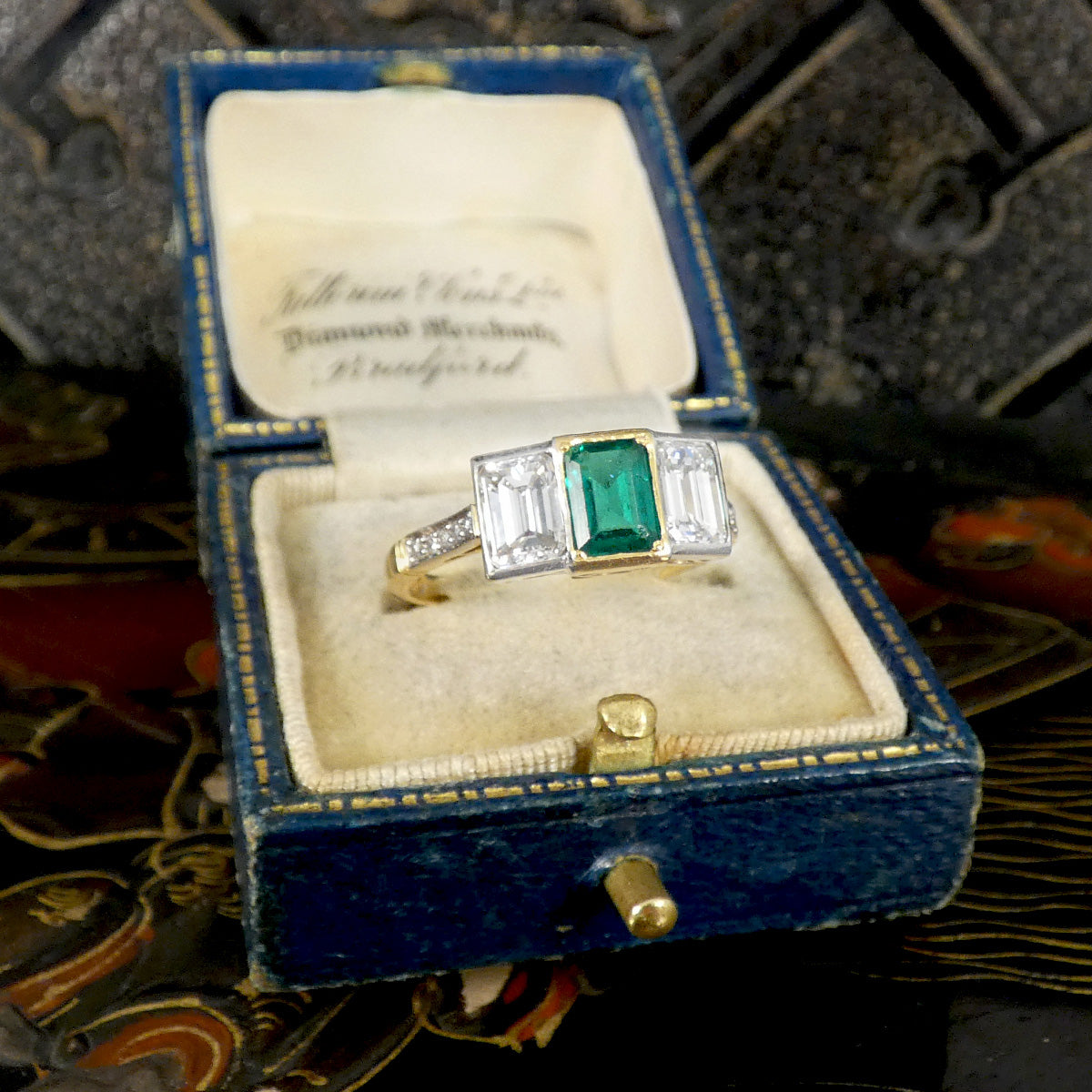 An Emerald and Diamond three stone ring in 18ct white and yellow gold displayed in box.