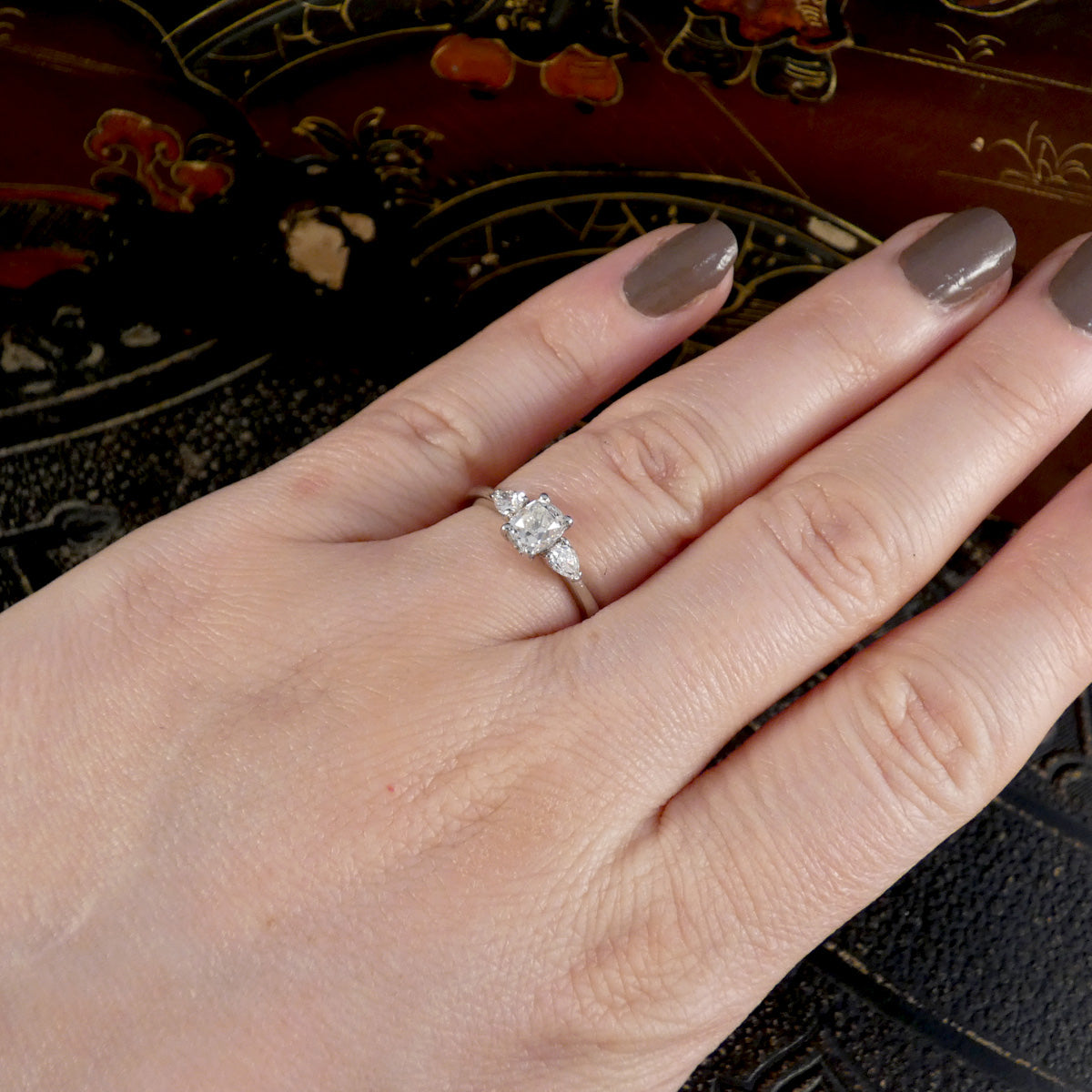 Hand wearing a diamond ring with a decorative background