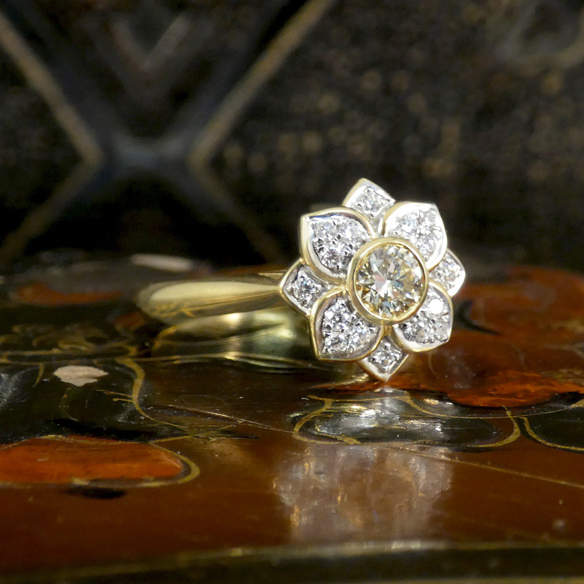Gold and diamond flower-shaped ring on a decorative surface