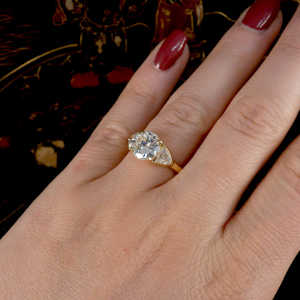 Gold ring with a diamond on a hand against a dark background