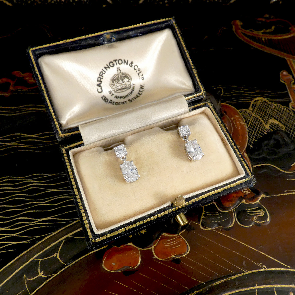 Diamond earrings in a Carrington & Co box on a decorative background