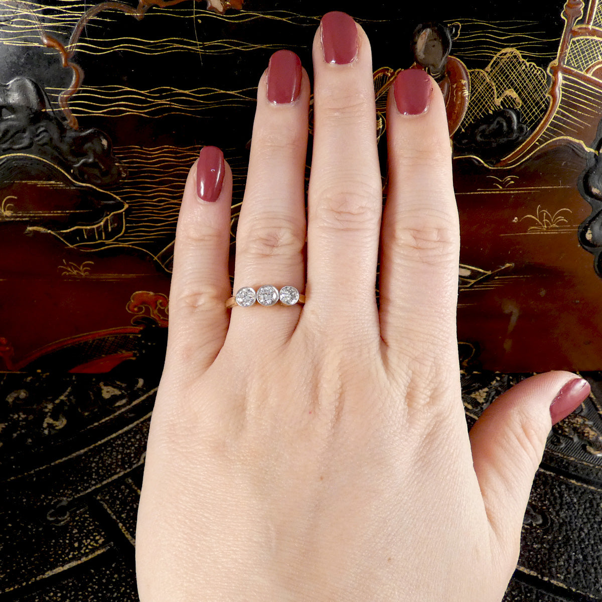 Hand wearing a diamond ring with a decorative background