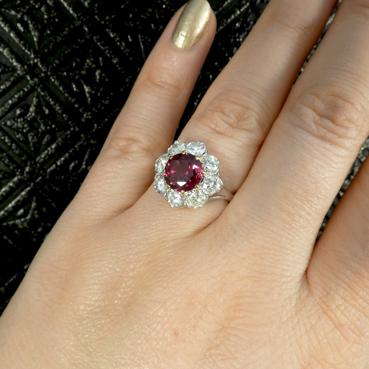 2.00ct Pyrope Garnet and 1.40ct Brilliant Cut Diamond flower cluster ring in 18ct White Gold with Yellow Gold claws on the Garnet. Showcased on the finger for size reference and displayed worn.