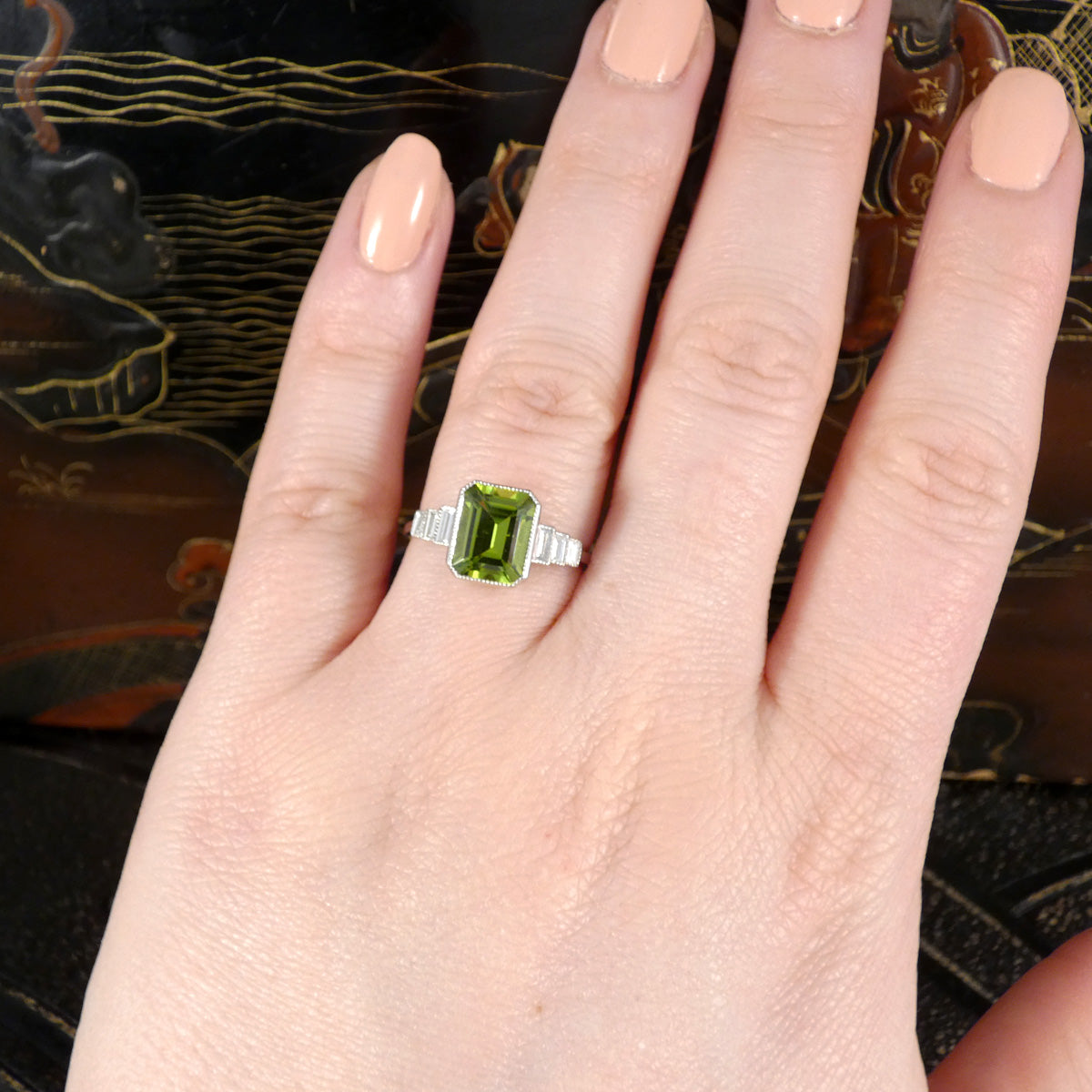 Art Deco Inspired Peridot and Baguette Cut Diamond Staged Shoulders in Platinum shown on the finger to see size ratio and colour.