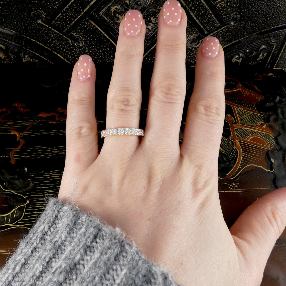 Hand wearing a diamond ring with a decorative background