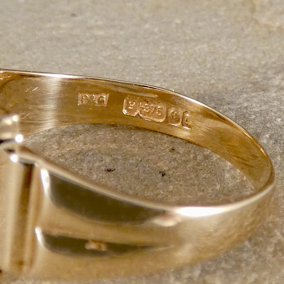 Gold ring with visible hallmarks on a textured surface