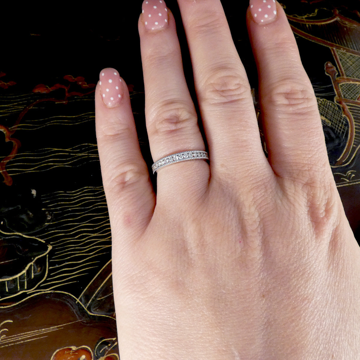 Hand wearing a diamond ring with a decorative background