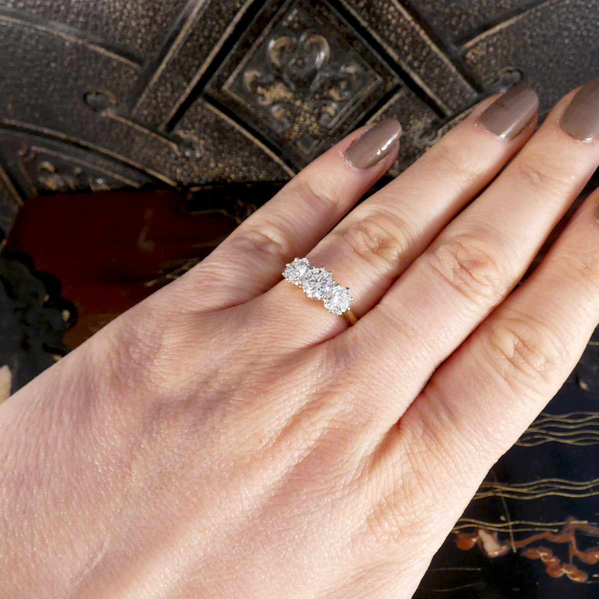Hand wearing a diamond ring with a textured surface background