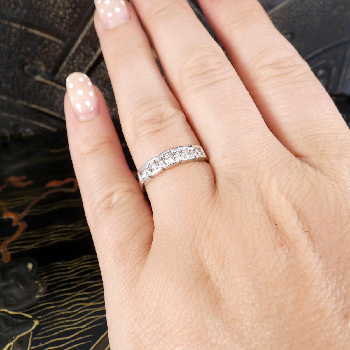Hand wearing a diamond ring on a dark textured background
