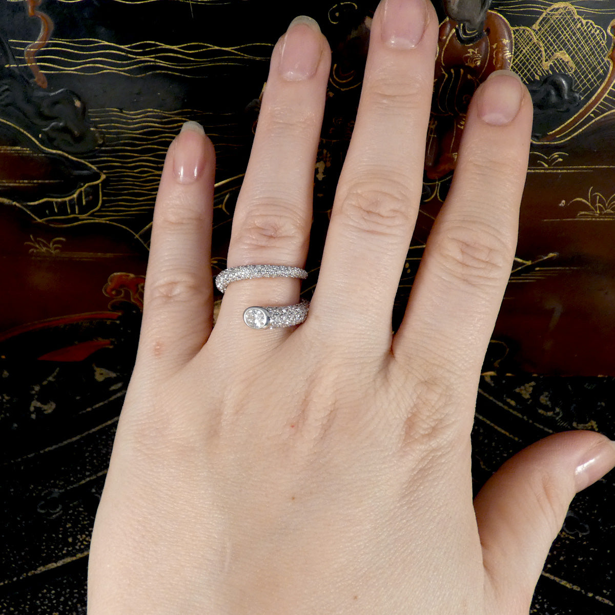 A unique diamond set snake like ring shown on the hand twisting round the finger.