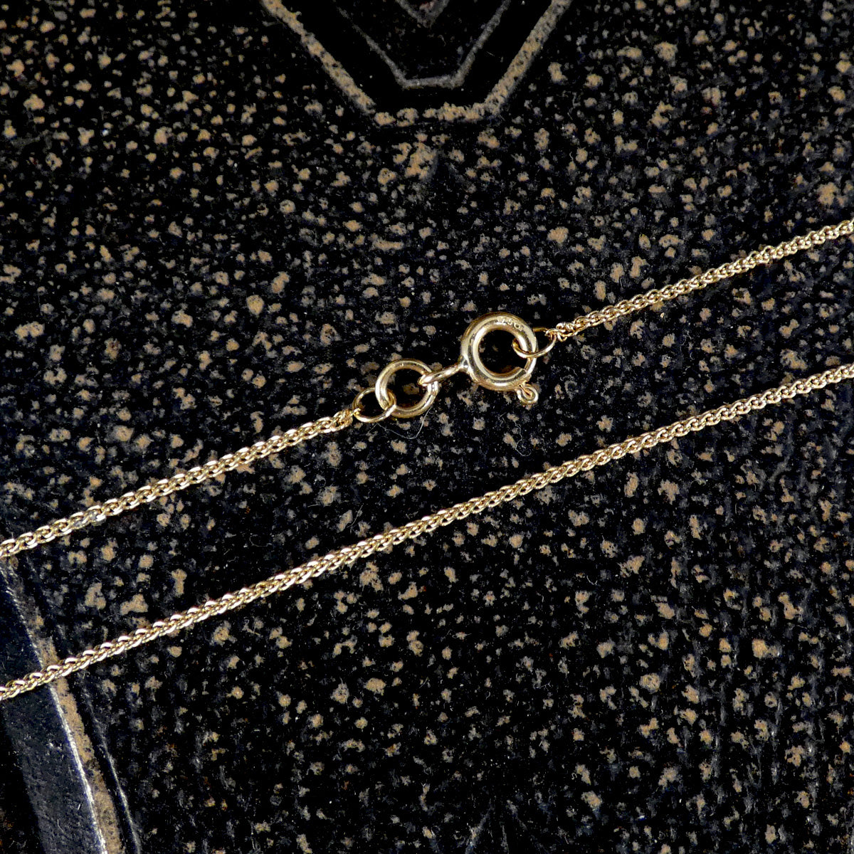 Gold chain necklace on a textured black background
