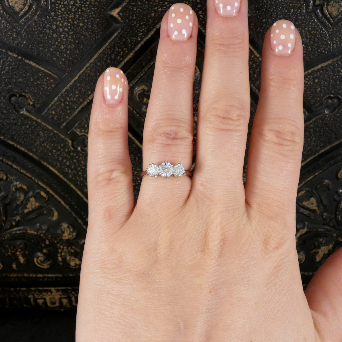Hand wearing a diamond ring with a decorative background