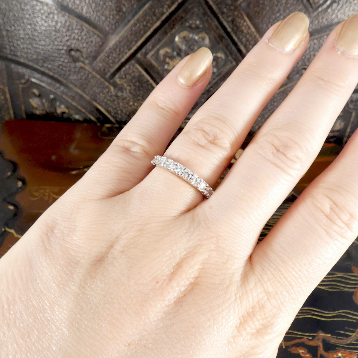 Hand wearing a diamond ring with a decorative background