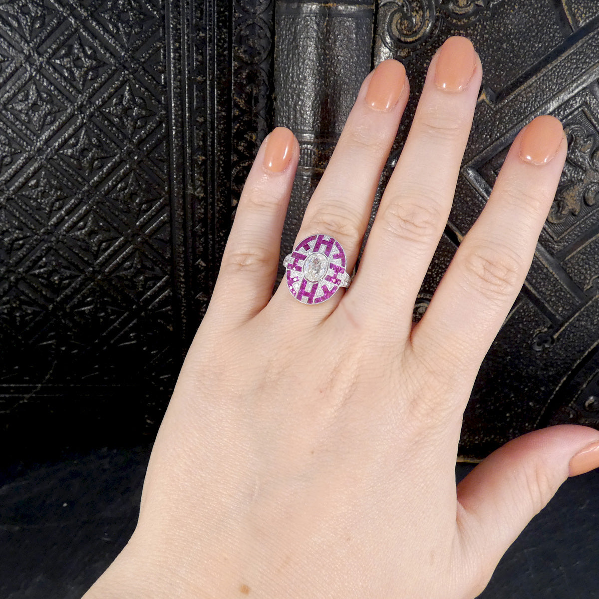 Art Deco Inspired Oval Cut Diamond Cluster Ring with Calibre Cut Rubies in Platinum shown on the hand to see to see size and shape reference. 