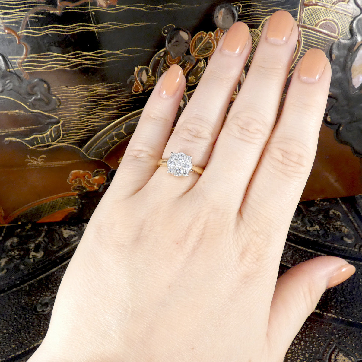 Hand wearing a diamond ring with a decorative background