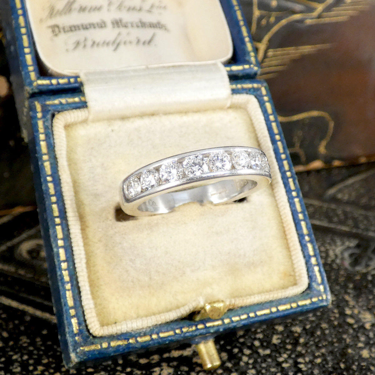 A diamond channel set ring in platinum shown in a jewellery box