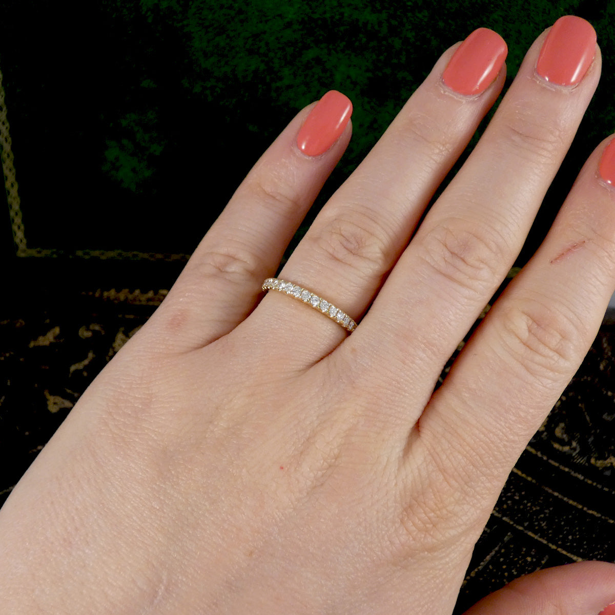 A diamond half eternity ring in yellow gold, displayed on the hand in ring finger