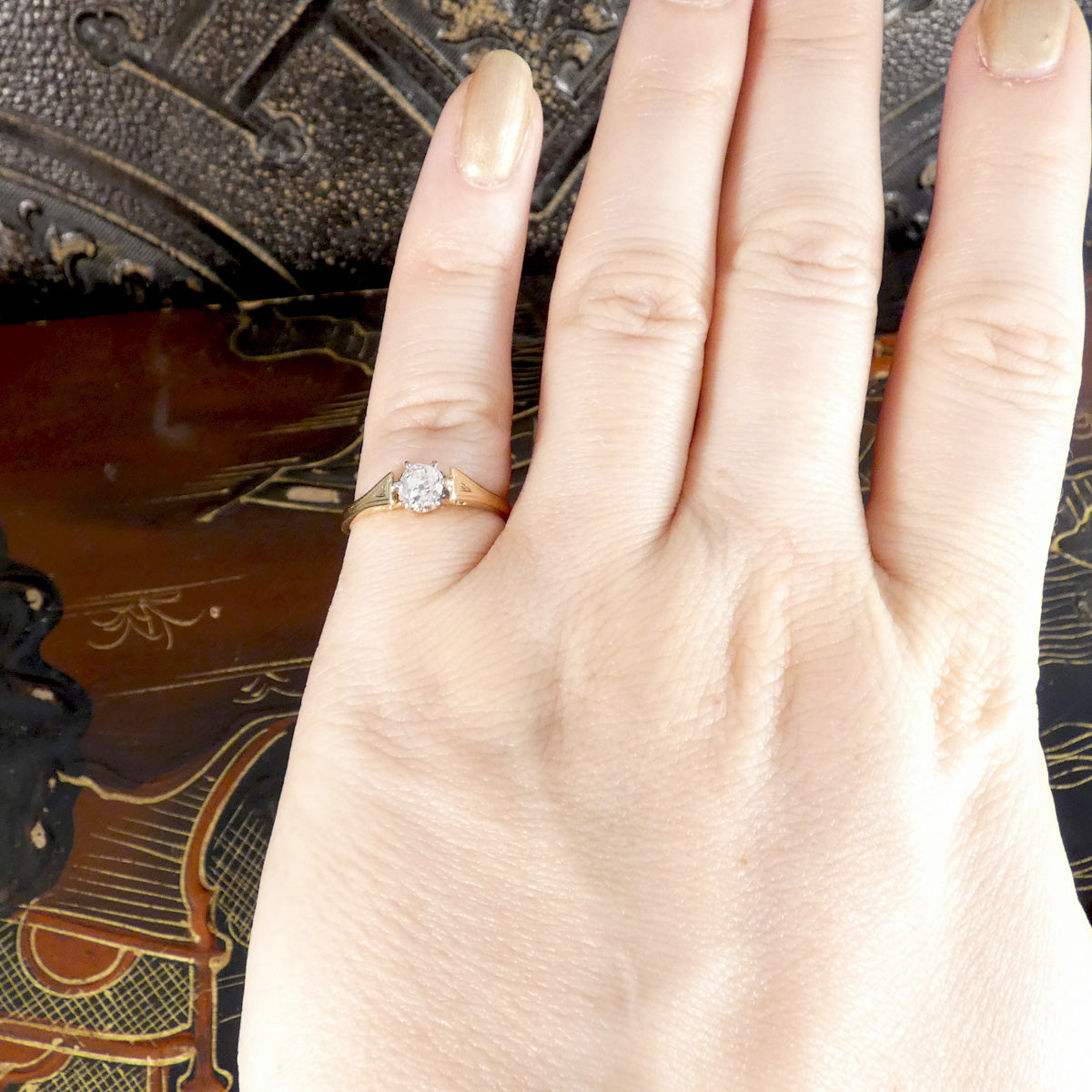 Hand wearing a gold ring with a diamond on an ornate background
