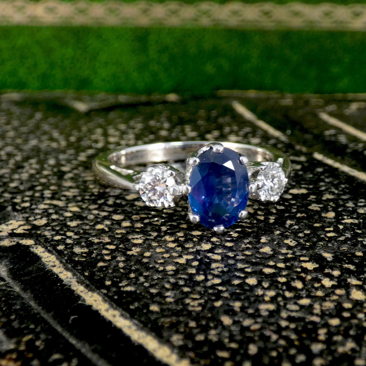 Sapphire and Diamond trilogy ring on a textured background 