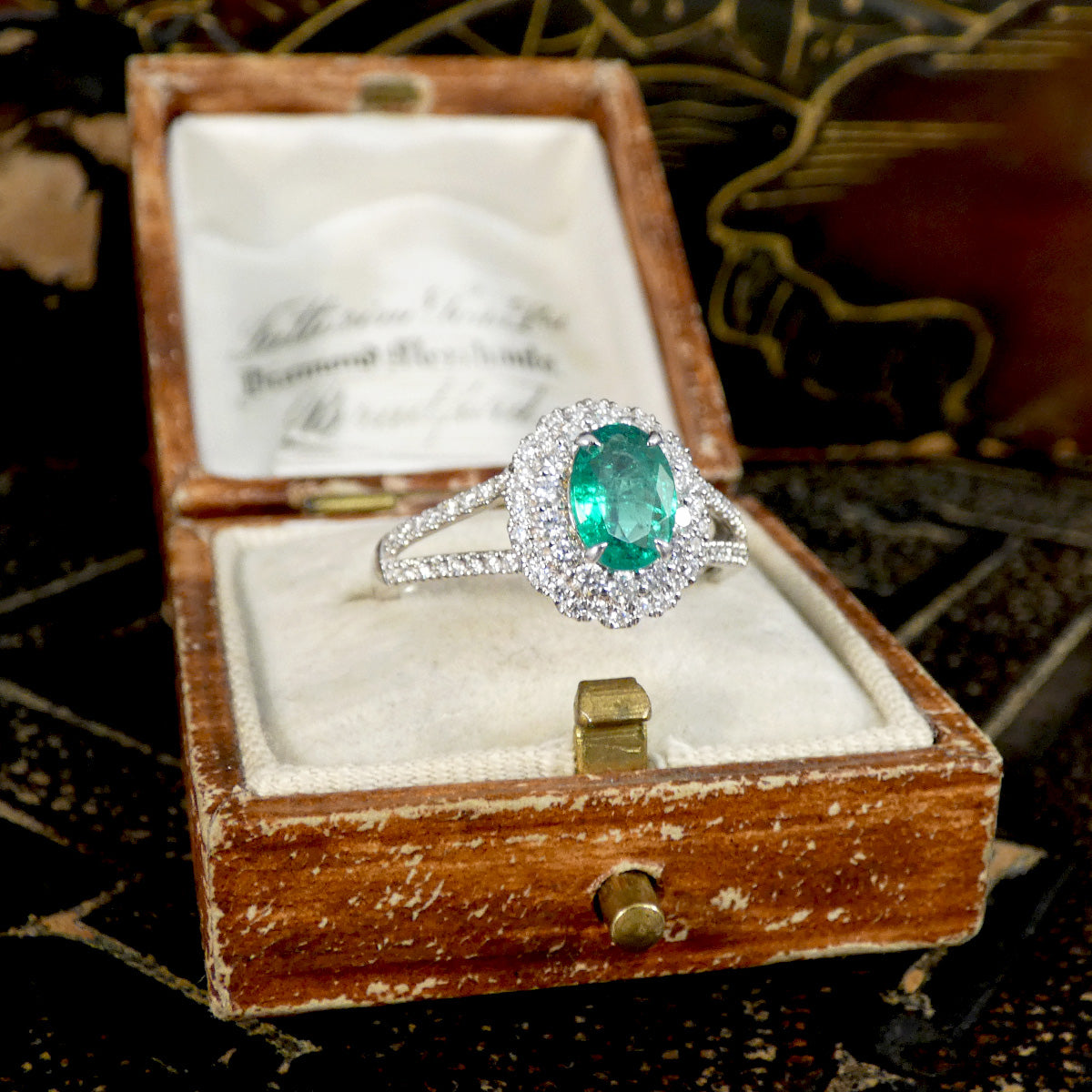Emerald ring in a wooden box with a decorative background