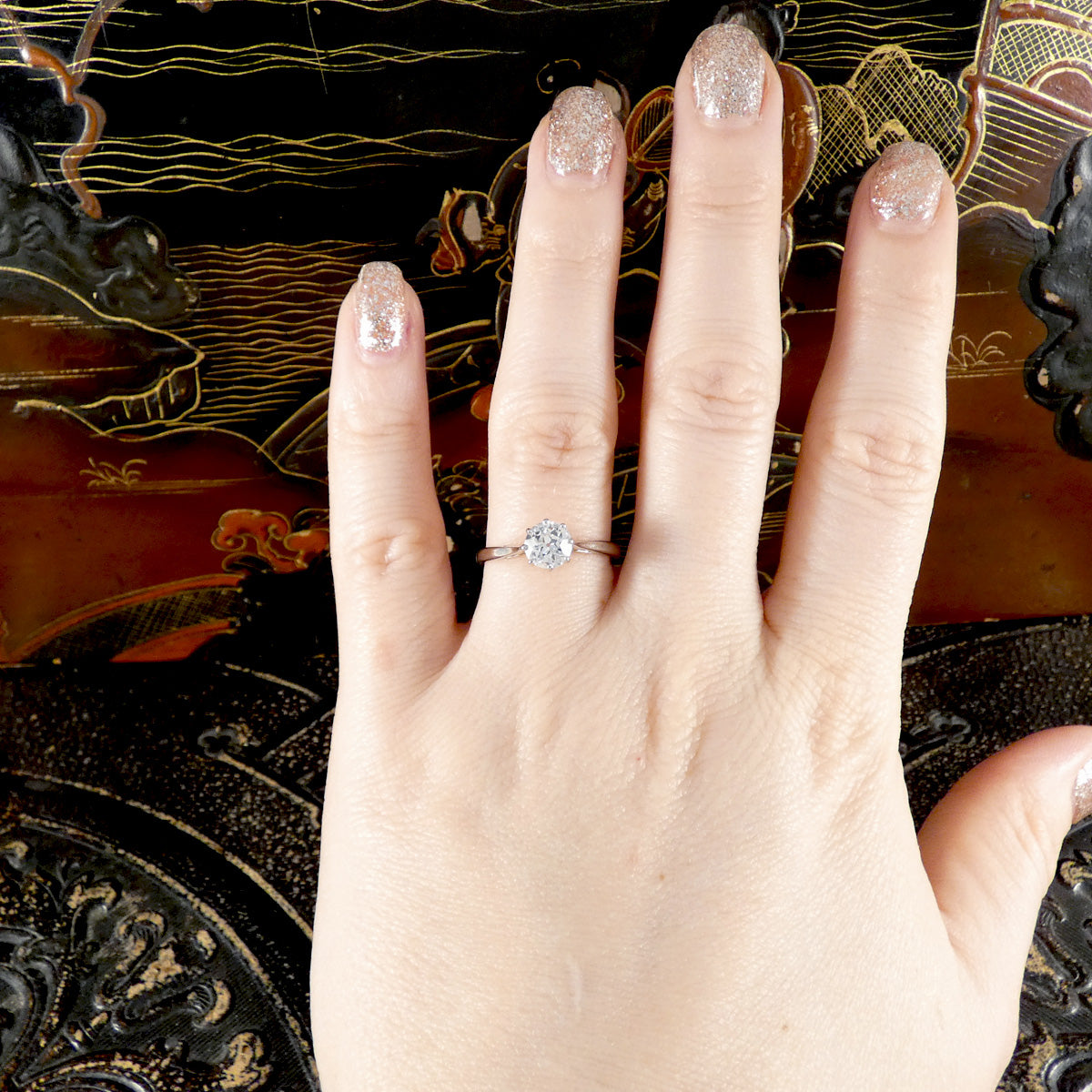 An old cut diamond solitaire ring in 18ct white gold and platinum shown on the ring finger on a hand.