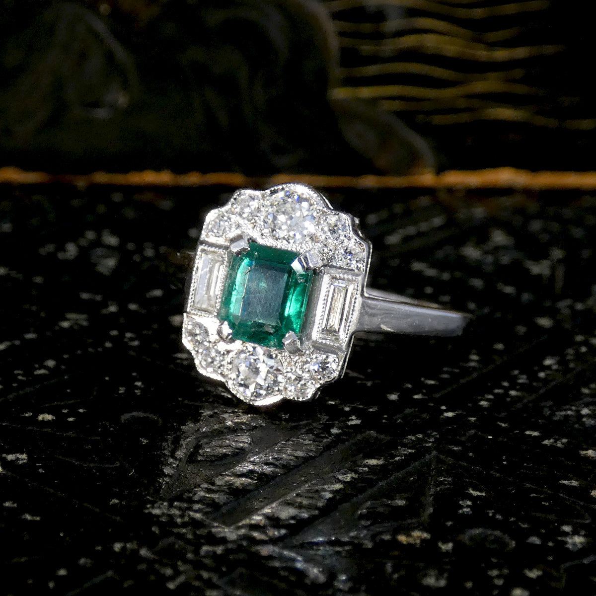 Art Deco Style Emerald and Diamond Cluster ring on a dark background