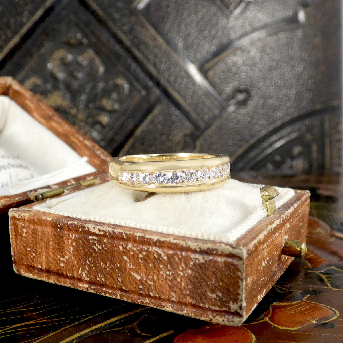 Gold ring with diamonds in a wooden box on a decorative surface