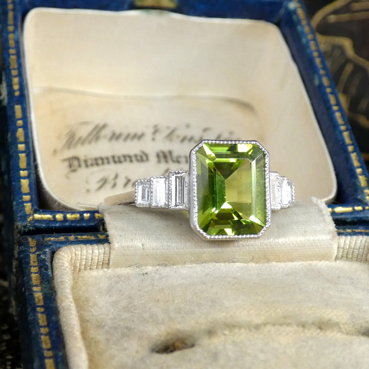Art Deco Inspired Peridot and Baguette Cut Diamond Staged Shoulders in Platinum displayed in vintage box.