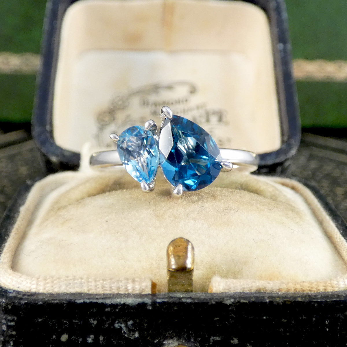 Silver ring with blue gemstones in an open jewelry box.