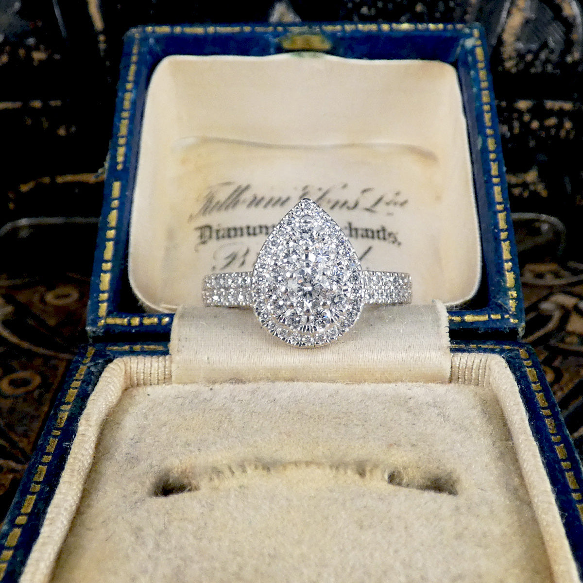 Diamond ring in an open jewelry box with a decorative background