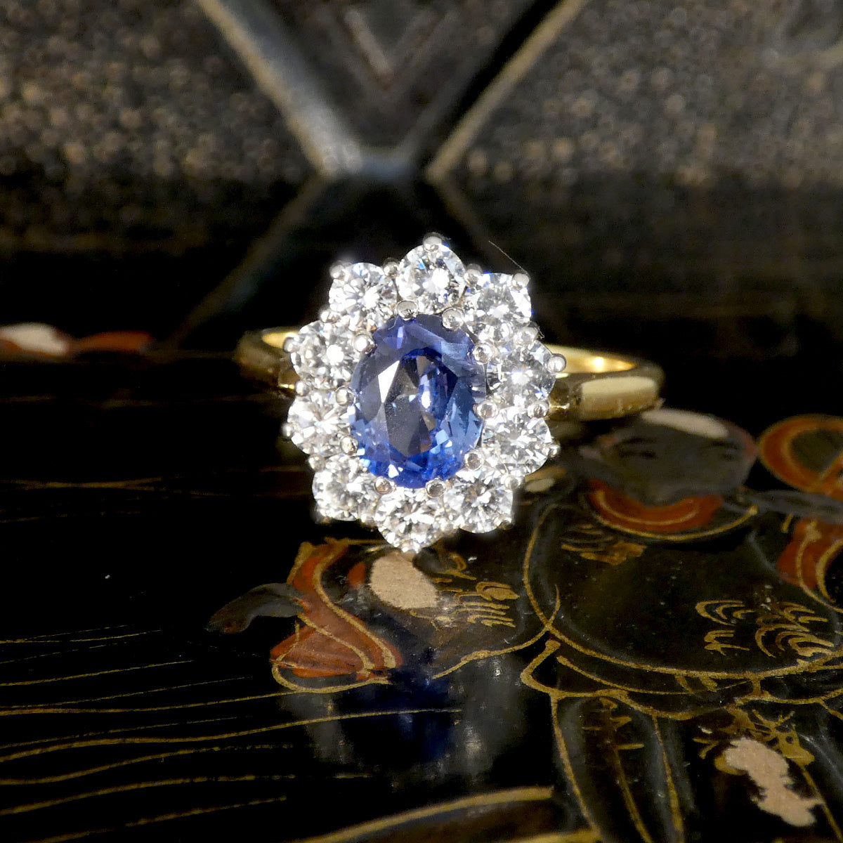 Gold ring with a blue gemstone and diamond halo on a decorative surface in large size