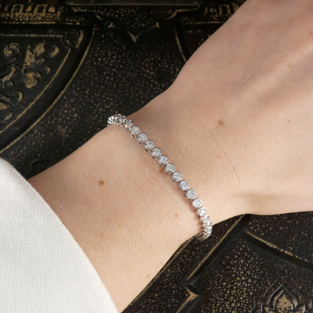 A diamond tennis bracelet in a bezel setting in Platinum shown on the wrist