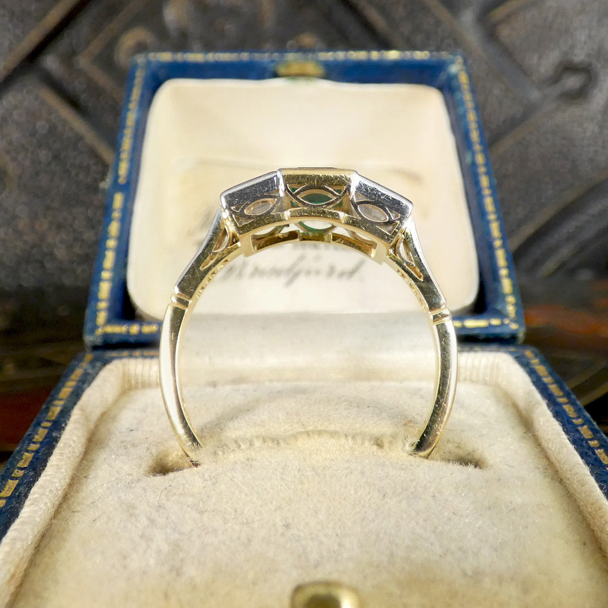 An Emerald and Diamond three stone ring in 18ct white and yellow gold showing gallery.