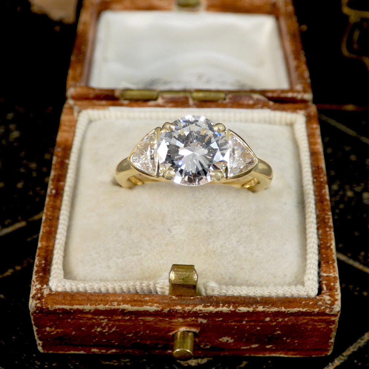 Gold ring with a large diamond in an open wooden box