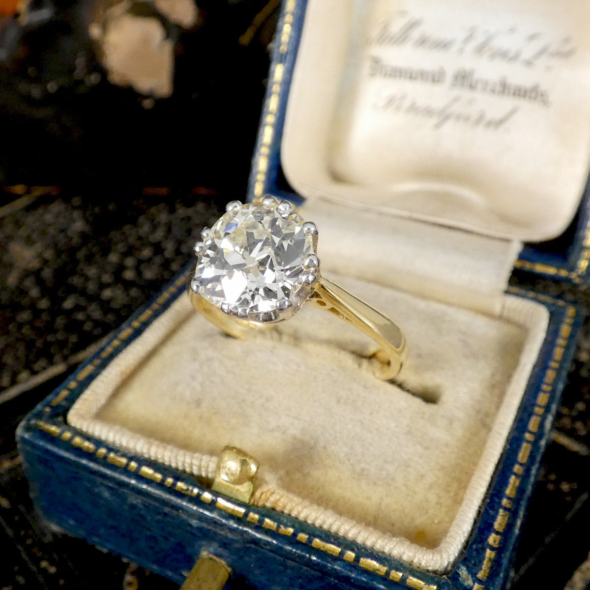 Gold ring with a large old cushion cut diamond in an open jewellery box