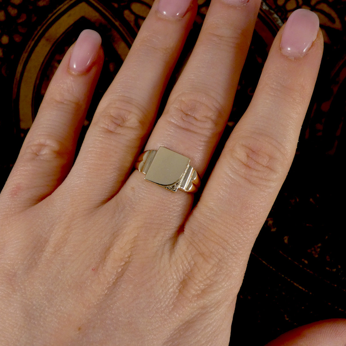 Gold ring on a person's finger with a dark background